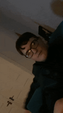 a man wearing glasses and a black shirt is sitting on a chair