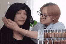 a woman in a hooded jacket is touching another woman 's neck .
