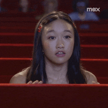 a woman sitting in a theater with the word max on the bottom left