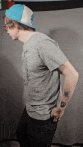 a man with a tattoo on his arm is wearing a hat
