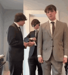 three young men in suits and ties are standing in a hallway