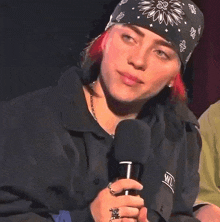 a woman wearing a bandana holds a microphone in her hand