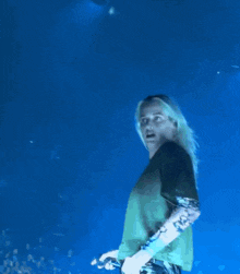 a man with long blonde hair is holding a microphone in his hand