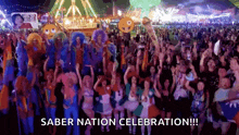 a large group of people are standing in front of a ferris wheel at a saber nation celebration .