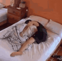 a man is laying on a bed with a blanket on his head