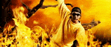 a man wearing sunglasses is standing in front of a fire .