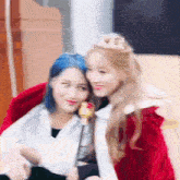 a couple of girls are sitting next to each other and one of them is wearing a crown .