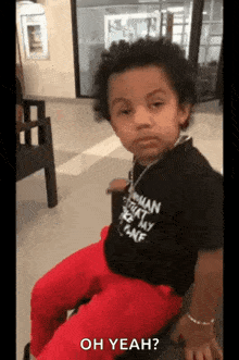 a little boy is sitting on a chair and making a face .