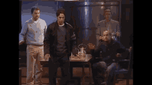 a group of men standing around a table with a tea kettle on it