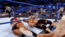 two men are wrestling in a wrestling ring with a referee in the background .