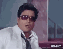 a man in a white shirt and tie is wearing sunglasses and making a funny face .