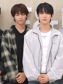 two young men standing next to each other with their eyes closed .