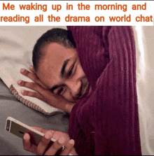 a man laying on a bed with a blanket over his head looking at a phone