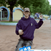 a man wearing a purple hoodie and a baseball cap is dancing
