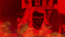 a man wearing headphones and sunglasses is surrounded by red flames