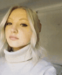 a woman with blonde hair wearing a white turtleneck