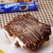 a white plate topped with a s'mores with oreos in the background