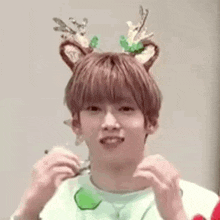 a young man wearing a reindeer headband and a green shirt .