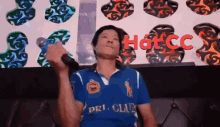 a man singing into a microphone wearing a blue shirt that says dri club