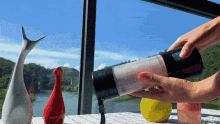 a person is pouring something into a blender on a table in front of a window