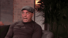 a man wearing a hat is making a funny face while sitting on a couch