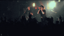 a man singing into a microphone while another man plays a guitar