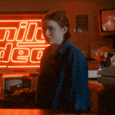 a woman is standing in front of a milk deer neon sign