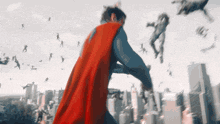 a man in a superman cape stands in front of a city skyline