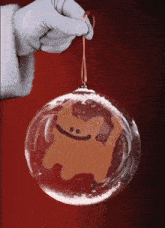 a hand is holding a christmas ornament with a gingerbread man inside