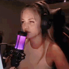 a woman wearing headphones and a bra is talking into a microphone .