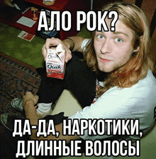 a man with long hair is sitting on a couch holding a carton of quik