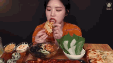 a woman is sitting at a table eating a piece of pizza .
