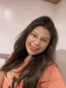 a woman wearing an orange shirt with the letter t on it is smiling