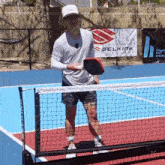 a man is playing a game of pickleball on a tennis court with a sign that says selkirk in the background