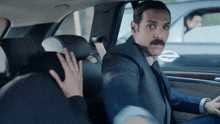 a man in a suit and tie is sitting in a car