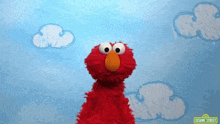 elmo from sesame street stands in front of clouds