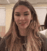 a young woman with long hair is smiling for the camera .