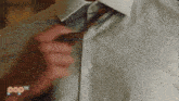 a man is adjusting his tie in front of a screen that says pop tv