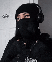 a woman wearing a mask and headphones is standing in front of a door
