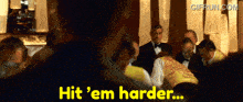 a man in a yellow vest says " hit 'em harder " in front of a crowd