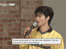 a man in a yellow striped shirt holds a microphone in front of a brick wall