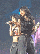two women singing on a stage with one wearing a tank top with the number 0 on it