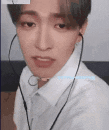 a young man wearing headphones and a white shirt is making a funny face .
