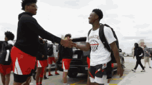 a man wearing an ohio state shirt shakes hands with another