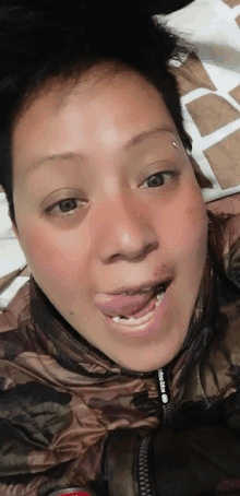 a woman laying on a bed with her tongue hanging out