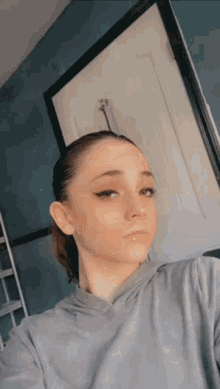 a girl taking a selfie in front of a blue wall