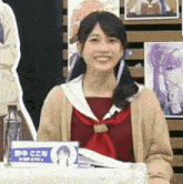 a woman sitting at a table with a name tag that says " ここな " on it