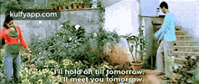 a man and a woman are standing in a garden and the man is saying " i 'll hold on till tomorrow .