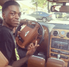 a young man is sitting in a bentley car and giving the middle finger