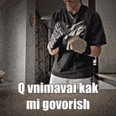 a man in a black shirt is holding a pair of gloves and says " q vnimavai kak mi govorish "